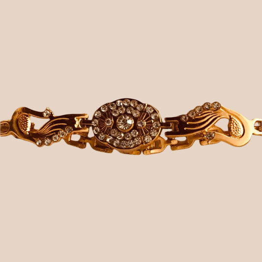 Gold bracelet with decorative clasp on a light fabric background
