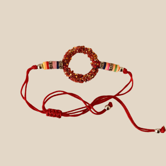 Red bracelet with colorful beads on a beige fabric background